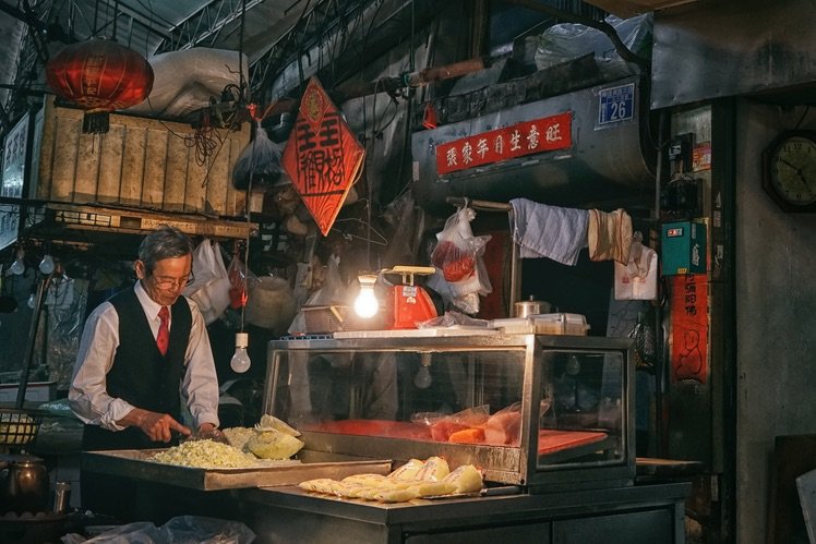 穿著整齊西服跟街邊的小店形成新舊上的對比。 Sony A7II, SEL2470Z, F5.6, 1/60s, ISO 1600